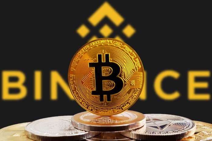 Bitcoin BTC pe un teanc de criptomonede cu logoul de schimb Binance în fundal. Moneda criptomonedă este de aur și focalizată. Copenhaga / Danemarca - 07 12 2018.