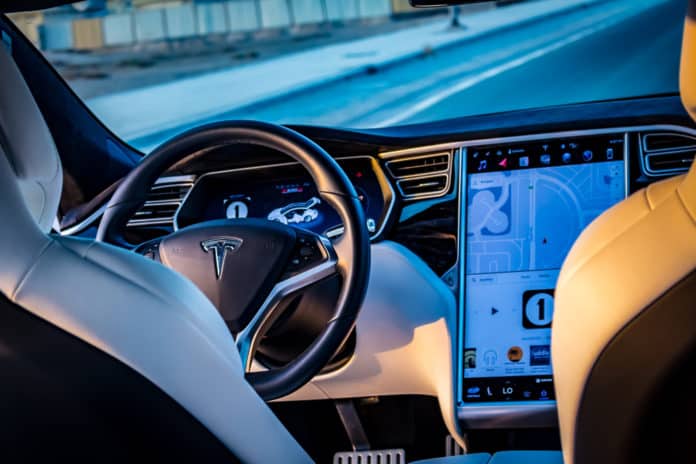 Дубай, Объединенные Арабские Эмираты - 08032018 Интерьер электромобиля Tesla Model S P100D на пустой дороге в Дубае на закате - изображение